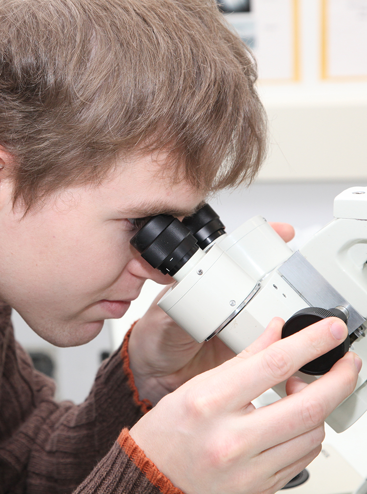 SUNY Poly student looks into a microscope