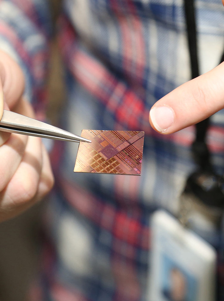 Graduate student holds and point to a silicon chip