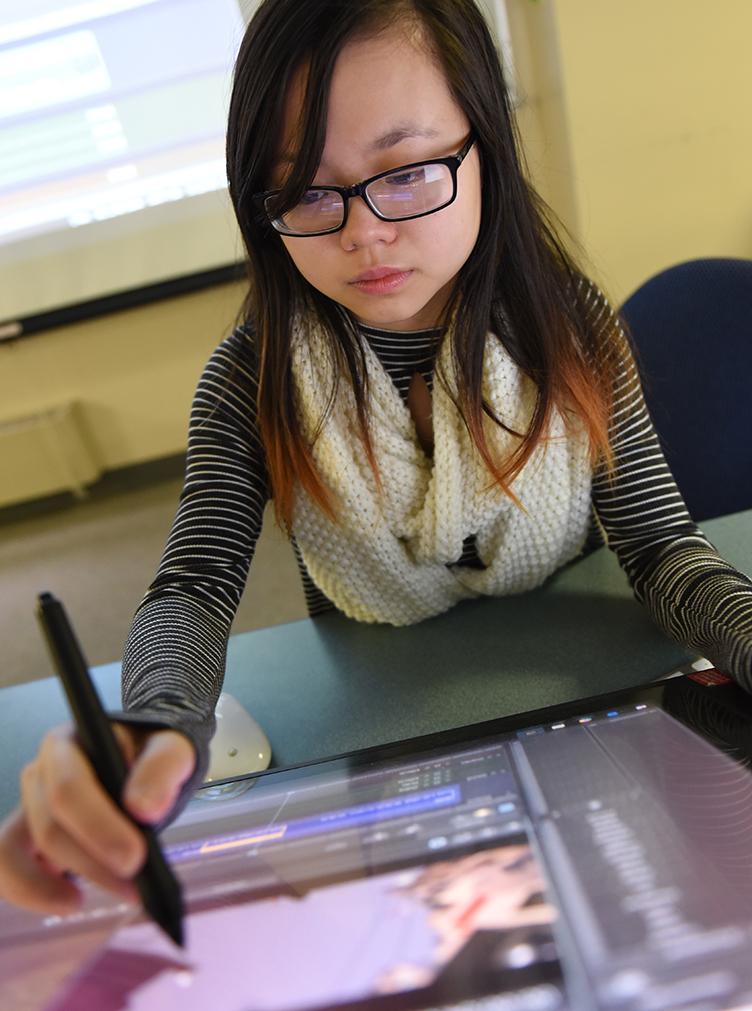 Student in front of a computer screen at SUNY Poly
