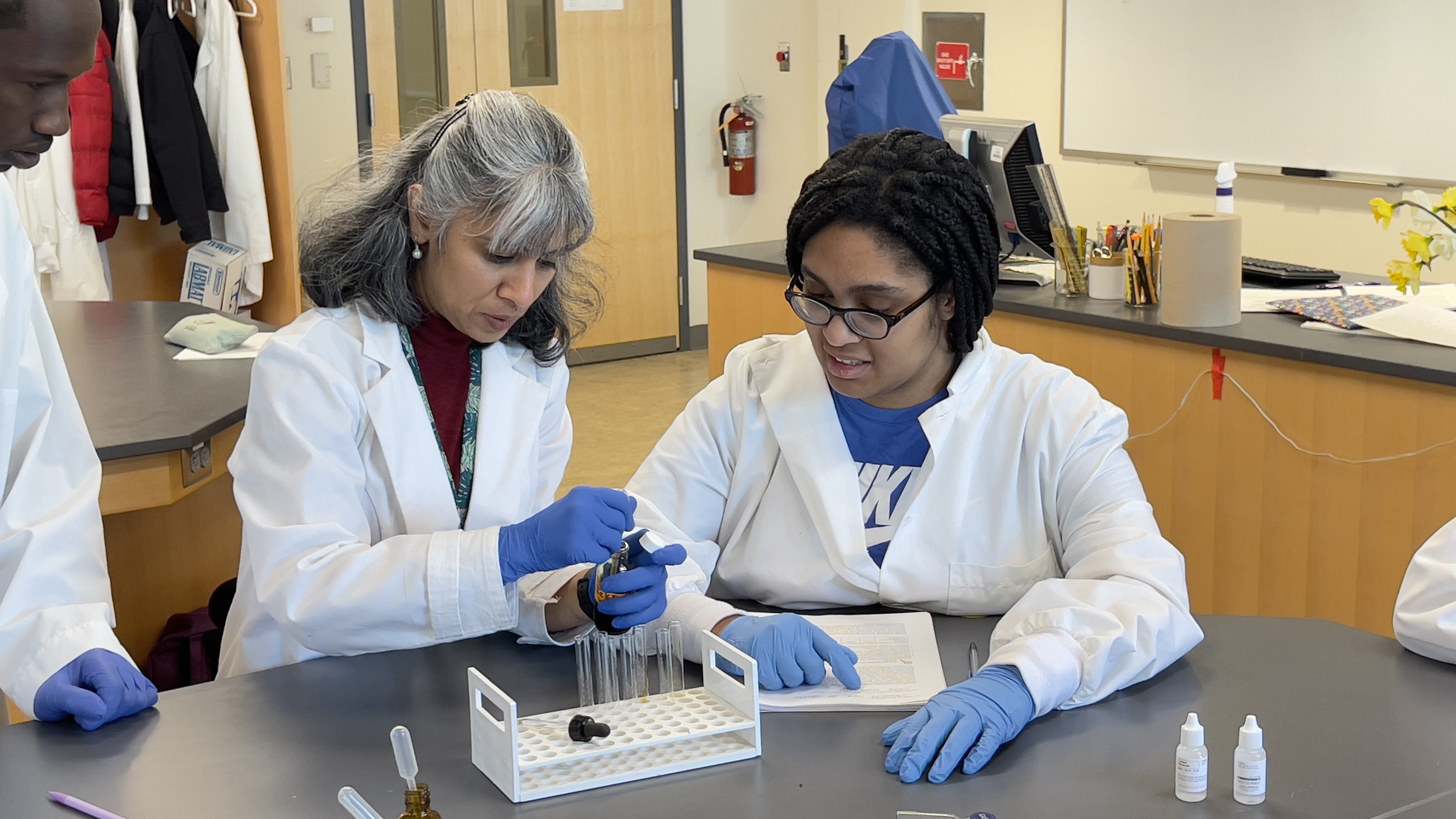 Biology professor guiding a student during laboratory work
