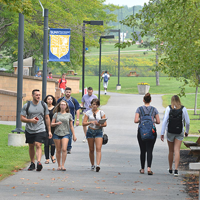 Students walk in front of Donovan Hall on the Utica campus