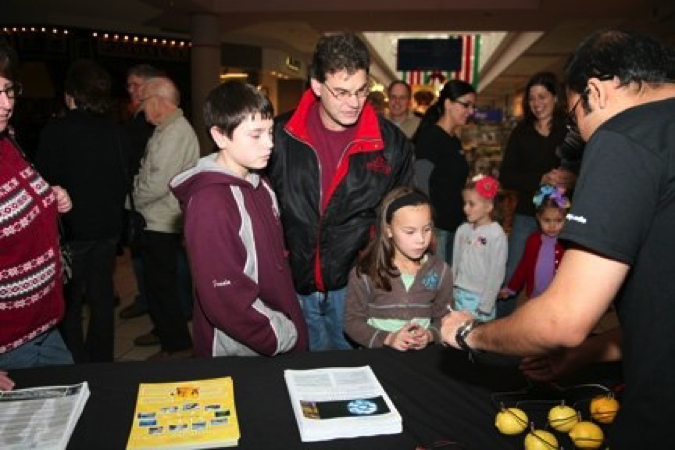 A Graduate Student does a science experiment for visitors