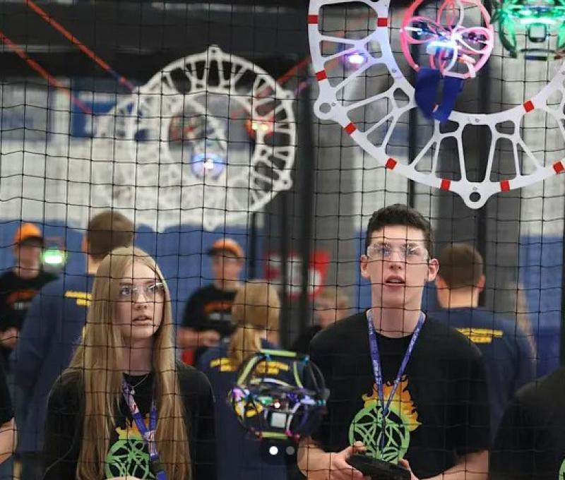 Two young people flying drones in drone soccer match
