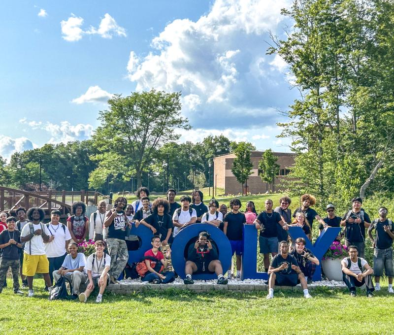 SUNY Poly Class of 2030 Incoming EOP class standing in front of the Poly sign on a perfectly sunny day